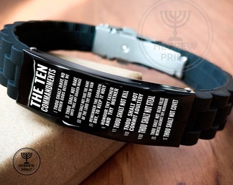 Op de afbeelding: Zwart siliconen armband met een zilveren metalen sluiting. De armband heeft een zwarte metalen plaat met de tekst "De Tien Geboden" en de tien geboden in witte tekst.