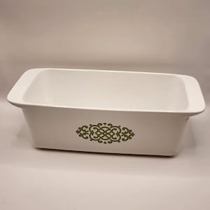 May include: White rectangular baking dish with rounded corners. The dish features a green decorative design on the front. The dish is empty and ready for use. A classic kitchenware item.