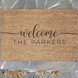 May include: A brown coir doormat with the text "welcome the parkers" in black cursive lettering.