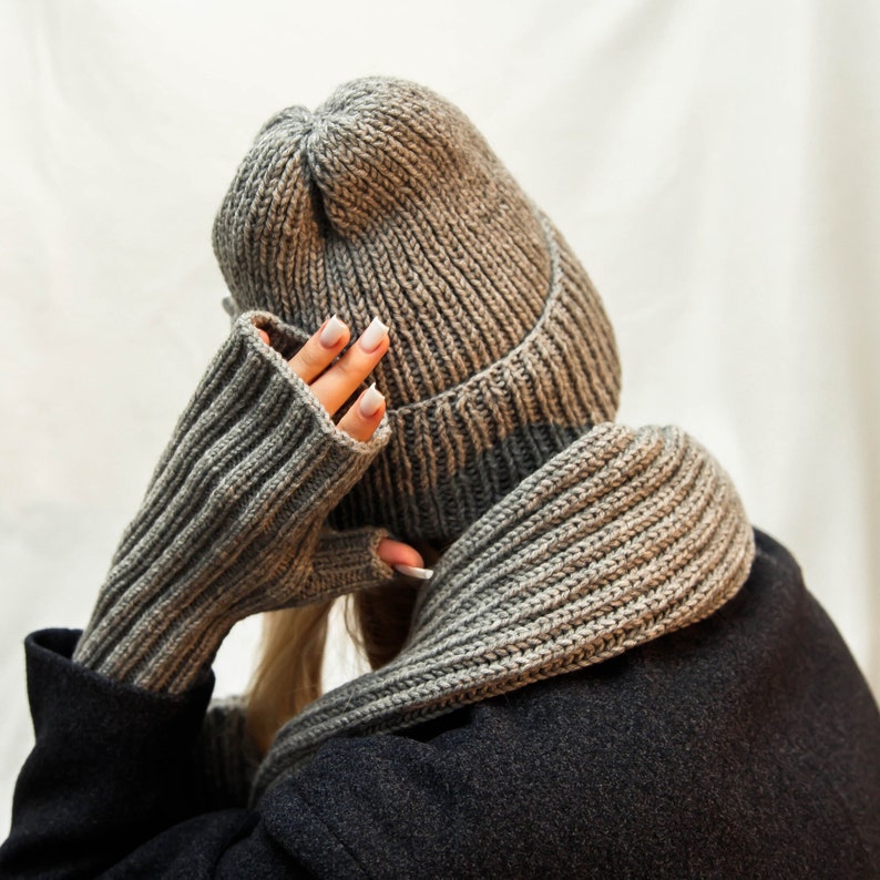 The image captures a person from behind, wearing a ribbed knit beanie that slouches at the back. The hat's material has a gradient of gray tones, emphasizing its cozy texture.