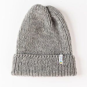 The picture shows a knit beanie laid out against a white background. It features ribbed texturing, a folded brim with a visible logo tag.