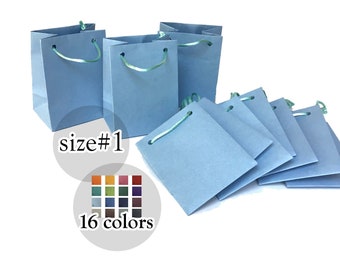 May include: A set of 10 light blue gift bags with green handles. The bags are arranged in a stack with the text "size #1" and "16 colors" below the stack. The colors are shown in a small square grid.