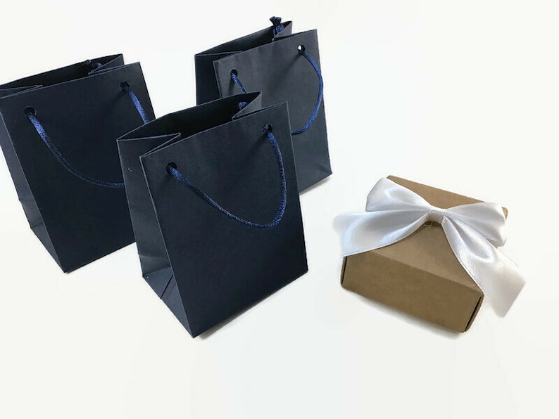 May include: Three dark blue paper gift bags with navy blue handles and a brown gift box with a white satin ribbon.