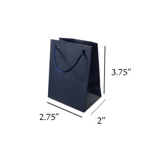 May include: A small, dark blue gift bag with a navy blue rope handle. The bag measures 3.75 inches tall, 2.75 inches wide, and 2 inches deep.