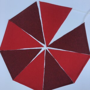 K&ouml;nnte beinhalten: Ein rotes und weinrotes Stoffbanner mit einer wei&szlig;en Schnur. Die dreieckigen Flaggen wechseln sich in der Farbe ab und erzeugen ein auff&auml;lliges visuelles Muster. Die Kanten jeder Flagge haben eine dekorative Zickzack-Borte. Ideal f&uuml;r festliche Dekorationen.