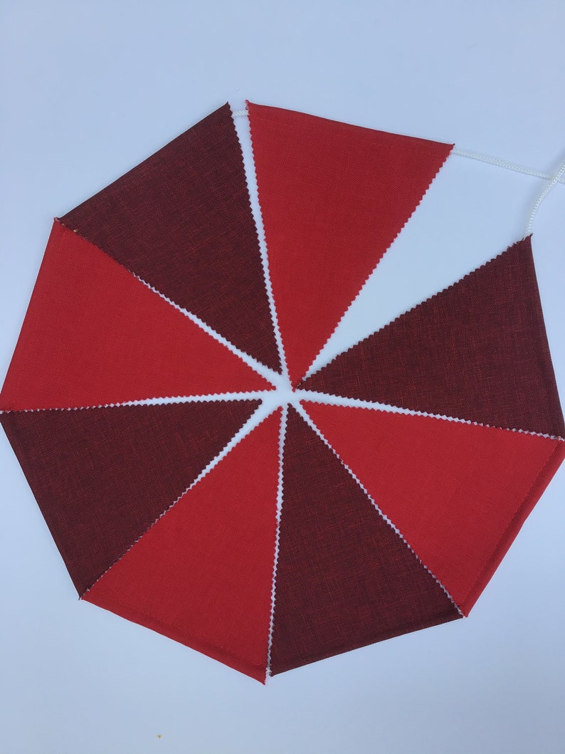 K&ouml;nnte beinhalten: Ein rotes und weinrotes Stoffbanner mit einer wei&szlig;en Schnur. Die dreieckigen Flaggen wechseln sich in der Farbe ab und erzeugen ein auff&auml;lliges visuelles Muster. Die Kanten jeder Flagge haben eine dekorative Zickzack-Borte. Ideal f&uuml;r festliche Dekorationen.