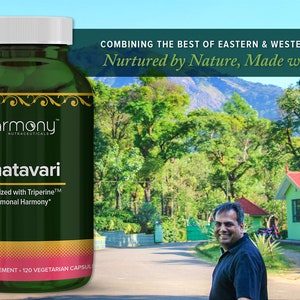 May include: A green bottle of Shatavari herbal supplement with the words "Harmony Nutraceuticals" and "Synergized with Triperine&trade; Hormonal Harmony&trade;" on the label. The bottle is sitting on a table in front of a green landscape with houses in the background.