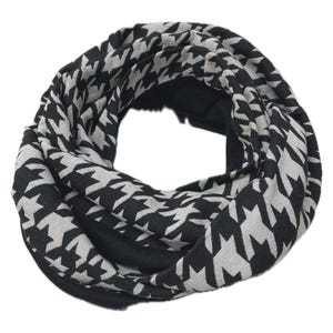 Könnte beinhalten: Ein schwarzer und weißer Schal mit Hundszahnmuster. Der Schal ist eine Endlosschleife, wobei das Hundszahnmuster die äußere Schicht bedeckt. Die Innenschicht ist einfarbig schwarz. Dieses Accessoire ist für kaltes Wetter geeignet.
