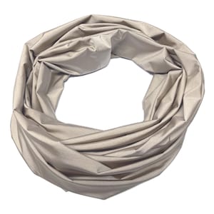 Könnte beinhalten: Beiger Infinity-Schal aus weichem, fließendem Stoff. Der Schal ist kreisförmig angeordnet, mit Falten und Knitterfalten, die Textur erzeugen. Die neutrale Farbe macht ihn zu einem vielseitigen Accessoire.