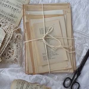 May include: A stack of vintage paper documents tied together with twine, sitting on a white lace tablecloth. The papers are yellowed with age and have a rustic, antique aesthetic.