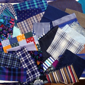 Könnte beinhalten: Eine Sammlung von Stoffresten in verschiedenen Blautönen und Weiß, mit karierten, gestreiften und einfarbigen Mustern. Die Stoffe sind in einem zufälligen Muster angeordnet und schaffen so eine optisch interessante und strukturierte Darstellung.