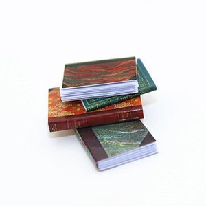 May include: A stack of three miniature books with colorful patterned covers. The top book has a red, orange, and green pattern, the middle book has a green and gold pattern, and the bottom book has a blue and green pattern.