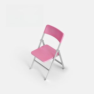 May include: A pink folding chair with a metal frame. The chair is folded and sitting on a white background.