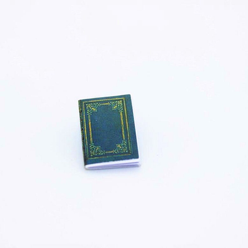 May include: A small, dark green book with a gold decorative border on the cover.