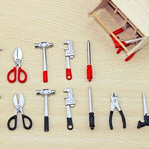 May include: A set of miniature tools, including a hammer, pliers, scissors, screwdrivers, and wrenches. The tools are made of metal and have red and black accents.