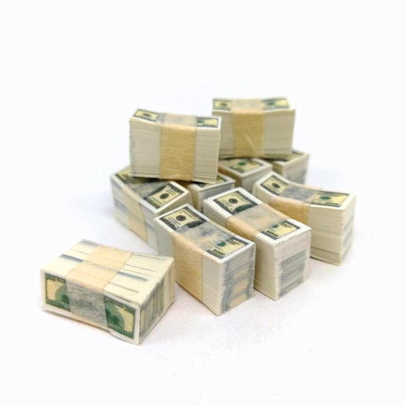 May include: A stack of ten fake money bundles, each wrapped in a tan band, with a green dollar bill design. The bundles are arranged in a pyramid shape.