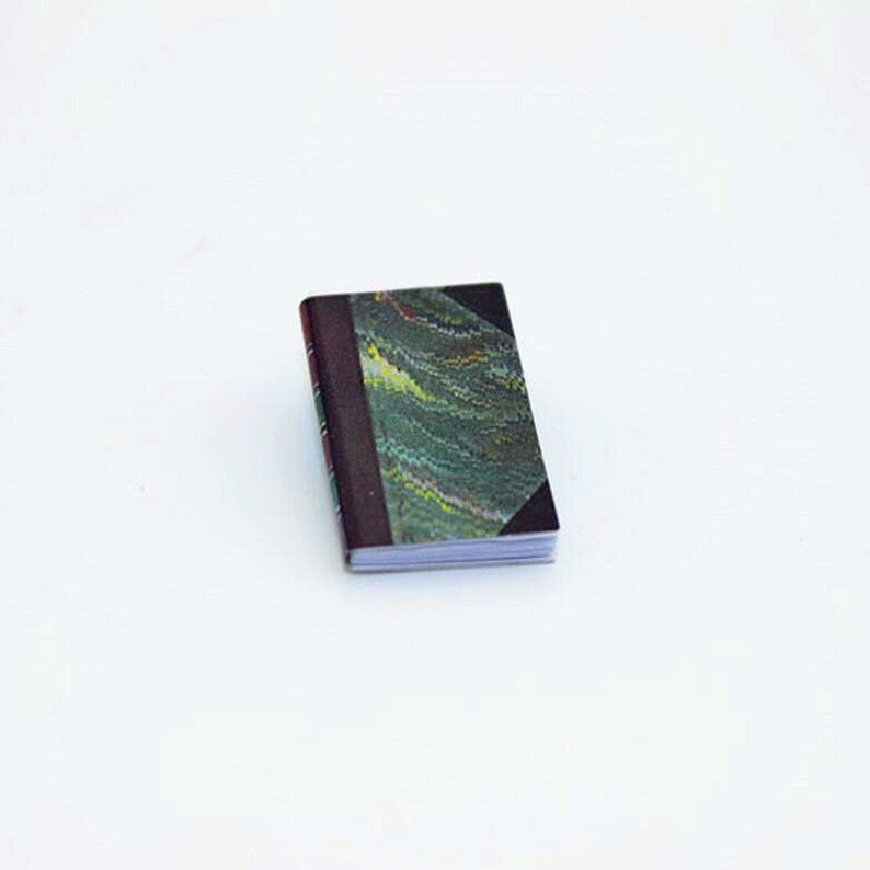 May include: A small, closed book with a dark green and brown marbled cover. The book is closed and the spine is visible.