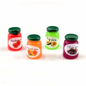 May include: Four miniature glass jars of jam with green lids. The jars are filled with red, orange, green, and purple jam. Each jar has a label with a fruit image and the name of the jam: Strawberry Jam, Apricot Jam, Fig Jam, and Plum Jam.