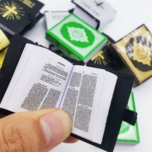 Puede incluir: Un libro en miniatura en blanco y negro con el t&iacute;tulo "Lev&iacute;tico" en la portada. El libro est&aacute; abierto en una p&aacute;gina con el texto "Lev&iacute;tico 1:1-17" y "Lev&iacute;tico 1:1-17".