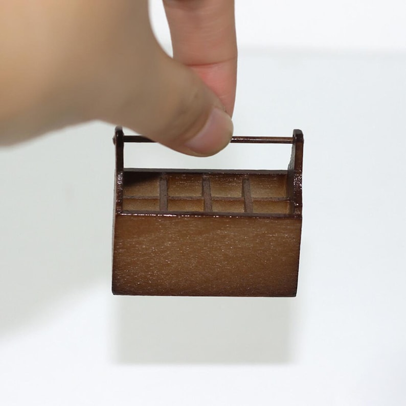 May include: A small wooden toolbox with a brown stain finish and a handle. The toolbox has multiple compartments.