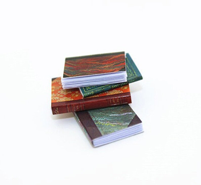 May include: A stack of three miniature books with colorful patterned covers. The top book has a red, orange, and green pattern, the middle book has a green and gold pattern, and the bottom book has a blue and green pattern.