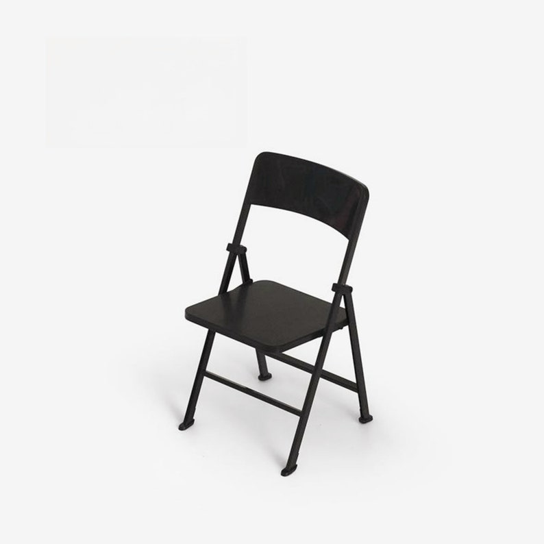 May include: A black folding chair with a simple design. The chair is made of metal and has a black finish.