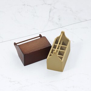 May include: Two wooden storage boxes with handles. One box is brown and the other is beige. The beige box has a grid pattern on the front.
