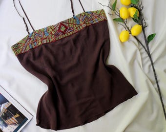 May include: A dark brown camisole featuring thin adjustable spaghetti straps and a wide horizontal band of intricate, multi-colored beadwork across the neckline in shades of red, blue, green, and yellow with a geometric pattern.