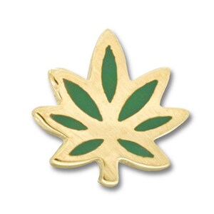 May include: A gold-toned metal lapel pin shaped like a seven-pointed leaf. The design features a polished gold border and a central inlay of matte green enamel filling the interior sections of each leaf segment, creating a distinct contrast.