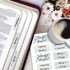 Könnte beinhalten: Ein Set rechteckiger, selbstklebender Bibelregister mit blau-grünem Blumenmuster und schwarzer Schrift. Die Register sind auf einem Bogen dargestellt und in einem Buch angebracht, mit Namen wie Matthew, Mark, Luke, Genesis, Exodus, Leviticus, Numbers, 2 Samuel, 1 Kings und 2 Kings.