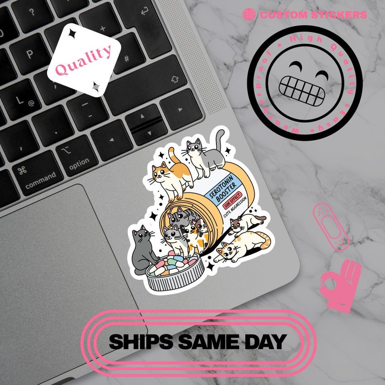 May include: A sticker featuring a cartoon illustration of cats spilling out of a pill bottle labeled "Serotonin Booster." The sticker has a playful design with the text "Cute Aggression" and "Quality."