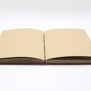 May include: An open book with brown paper pages and a purple linen cover.