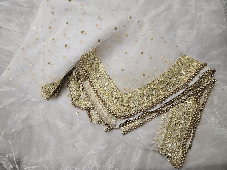 May include: White sheer scarf with gold embroidered trim and sequins. The scarf has a delicate, feminine look.