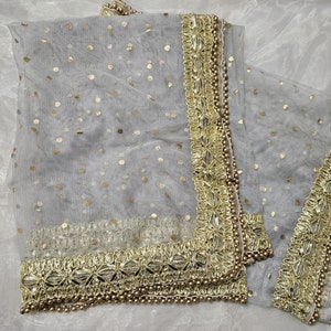 May include: A sheer gray scarf with gold polka dots and a gold embroidered border. The border has small gold beads.