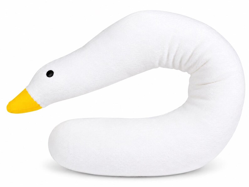 May include: A white plush pillow shaped like a goose neck with a curved body. The head features a bright yellow beak and a small, round black eye. The soft, textured fabric forms a continuous, elongated shape that mimics the neck and head of a bird.