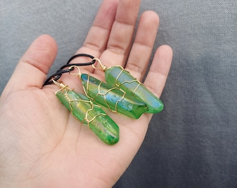 May include: Three green crystal pendants wrapped in gold wire, hanging from black cords. The pendants are in the shape of long, thin points.