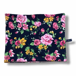 Könnte beinhalten: Ein dunkelblauer Stoff-Halswärmer mit einem rosa-gelben Blumendruck. Der Stoff ist weich, dehnbar und perfekt, um sich in den kälteren Monaten warm zu halten.