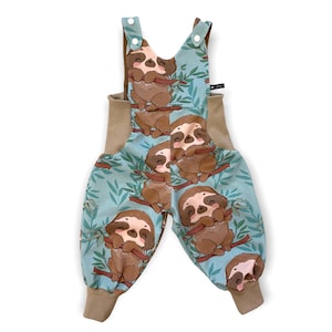 May include: Blue and brown baby overalls with a sloth print. The overalls have brown straps and brown cuffs.