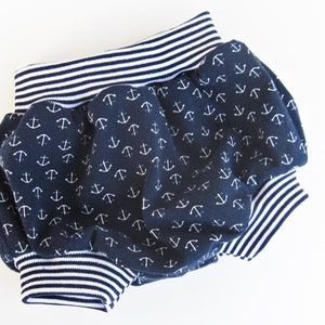 May include: Blue and white baby bloomers with an anchor print. The bloomers have a white and blue striped elastic waistband.