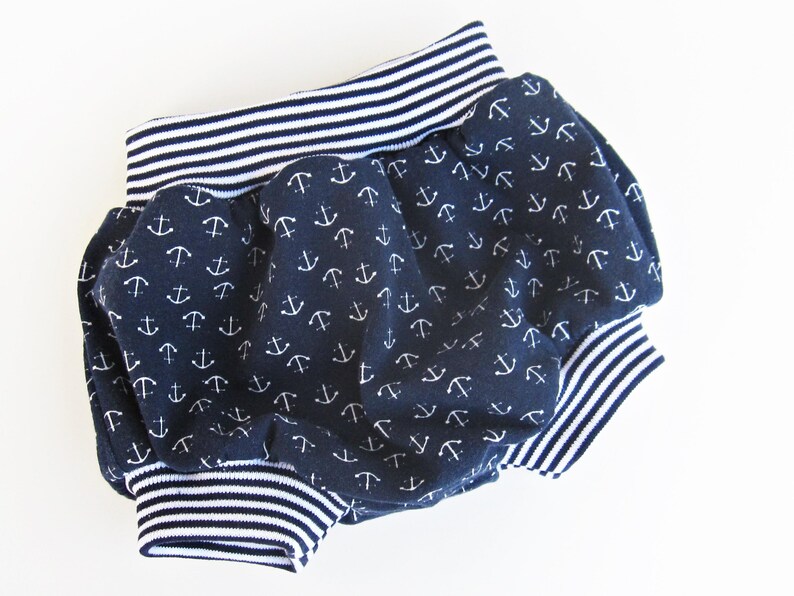 May include: Blue and white baby bloomers with an anchor print. The bloomers have a white and blue striped elastic waistband.