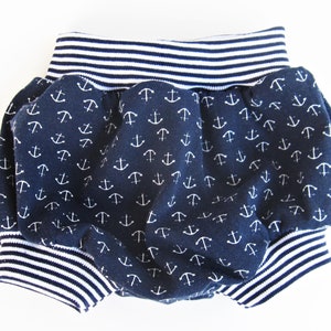May include: Blue and white baby bloomers with an anchor print. The bloomers have a white and blue striped elastic waistband.