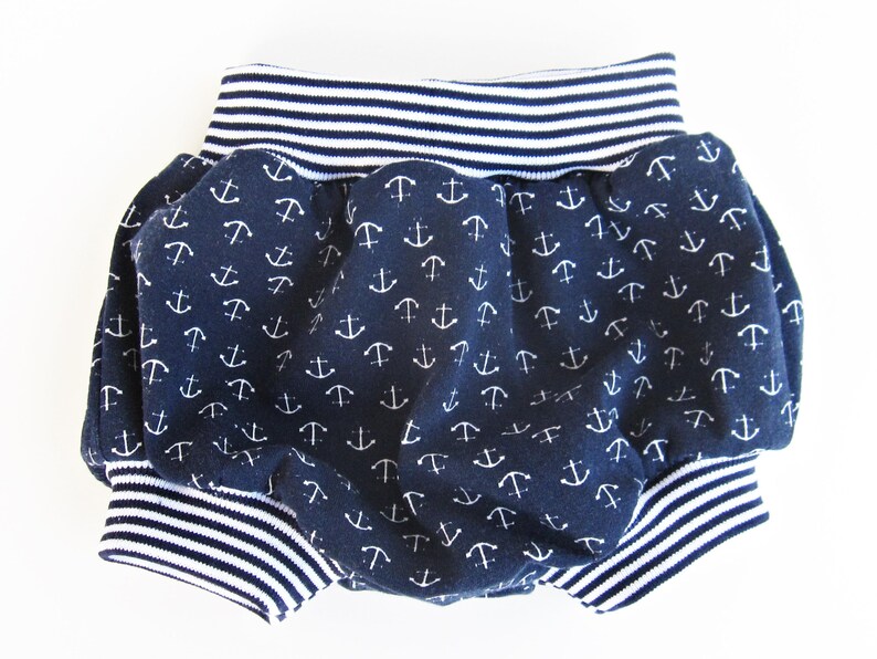 May include: Blue and white baby bloomers with an anchor print. The bloomers have a white and blue striped elastic waistband.