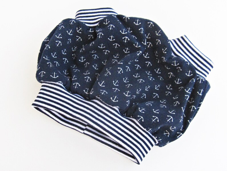 May include: A pair of navy blue baby bloomers with a white anchor print and white and navy blue striped trim.