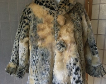 Puede incluir: Una chaqueta de piel sintética con estampado de leopardo. La chaqueta es de color crema, negro y marrón con una textura esponjosa.