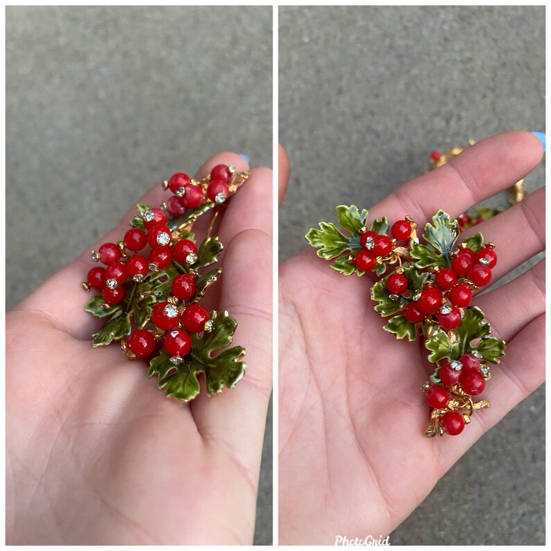 May include: A pair of gold-tone brooch pins with red enamel berries and green enamel leaves. The berries have small clear rhinestones.