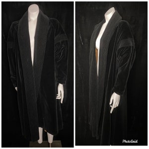 Puede incluir: Una larga bata de terciopelo negro con cuello chal y ribete acanalado. La bata está abierta por delante y tiene mangas largas.