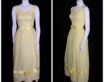 May include: A sleeveless yellow formal gown with a satin bow at the waist and a scalloped hemline.