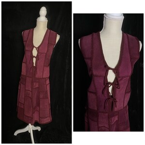 May include: A burgundy suede dress with a patchwork design and a tie-up detail at the neckline.