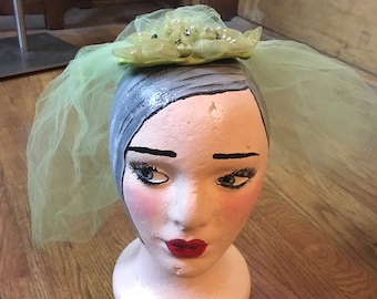 May include: A green tulle veil with a green and silver flower embellishment on top.