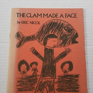May include: A red book cover with the title "THE CLAM MADE A FACE" by ERIC NICOL. The cover features a black and white illustration of a person holding a clam over their head.